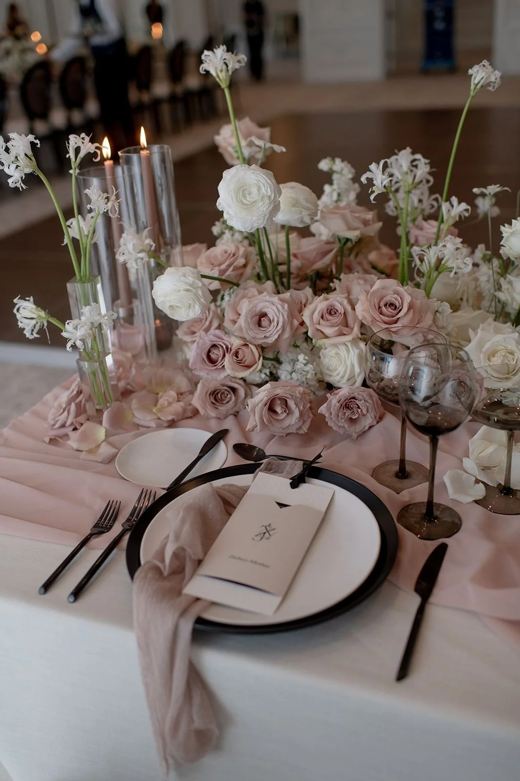 Blush rose centerpiece along a candlelit reception table