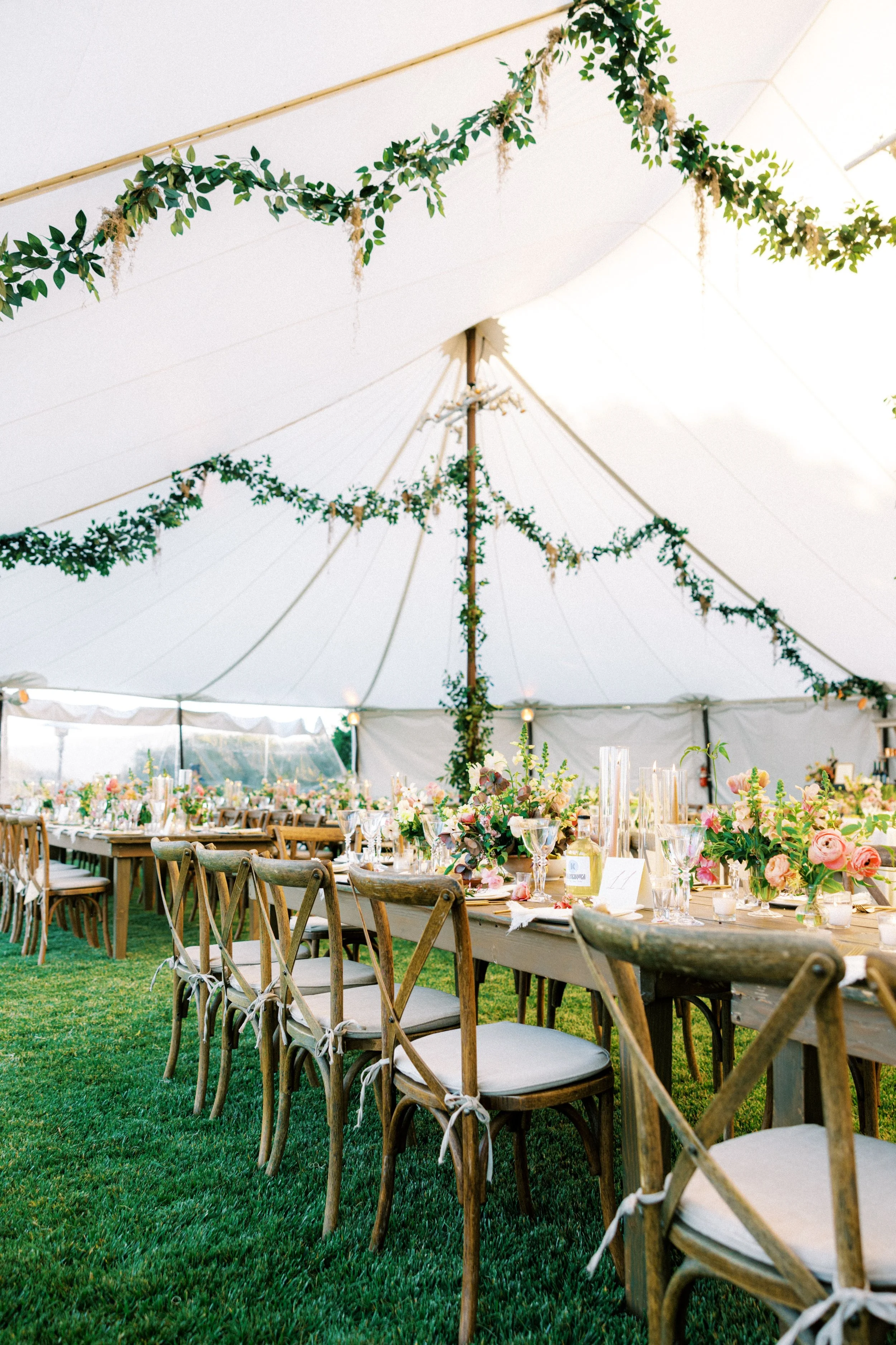 Tented reception with garland-draped poles at golden hour